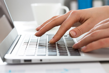 Close-up of hands of businesswoman typing on a laptop.