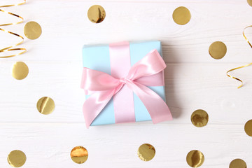 gift and sparkles of confetti on a colored background top view. minimalism, insta. flatlay 