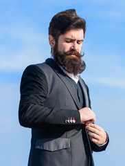 Fototapeta premium Flawless outfit. Businessman bearded face sky background. Man formal suit adjusting jacket. Male fashion formal menswear. Fashion trend. Guy beard and mustache wear formal clothes. Just right