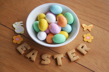 Easter background with colorful chocolate eggs in a bowl  with cookies on wooden background