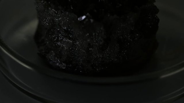 Light grey naturally occurring mineral standing in a glass laboratory utensils on the table. Stock footage. Chemistry experiments