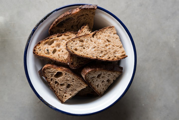 top view of sliced brown bread in white and blue enamel bowl on stone kitchen counter