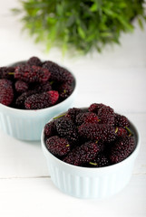 Fresh blackberries in bowl on white wooden background.