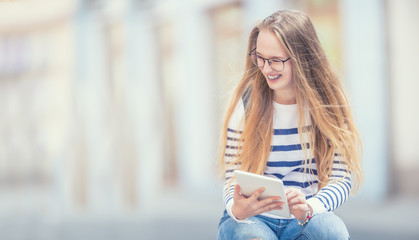 Portrait of a smiling beautiful teenage girl with dental braces. Young schoolgirl with school bag and tablet device