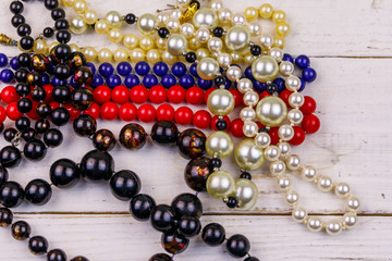 Different beads necklaces on white wooden background