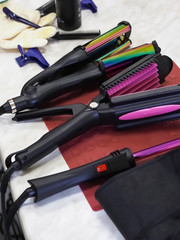 Various hair irons are laid out on the table.  