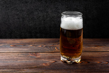 Beer and crisps on dark wooden background.