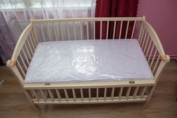 Fototapeta na wymiar new baby crib with mattress,bed with mattress for a girl in the bedroom is assembled