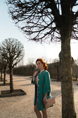 Young fashion lover woman waling in a park wearing vivid green jacket and a colorful skirt