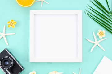 White frame with copy space, oranges, starfishes and retro camera. Top view light blue mint table. Travel mockup concept flat lay