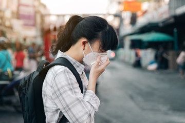 Asian woman wearing face mask coughing because of air pollution in the city