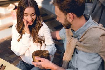 overhead view of surprised woman looking at heart-shape box in hand of boyfriend
