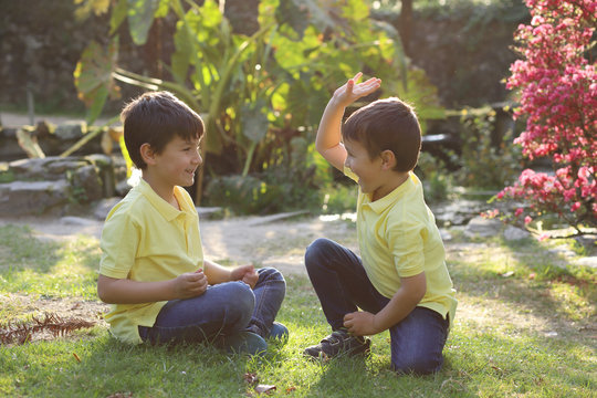 ni&ntilde;os felices jugando a chocar los pu&ntilde;os en el jard&iacute;n al atardecer
