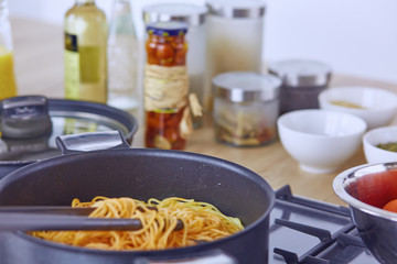 Pasta rolled on fork over pan on stove in the kitchen