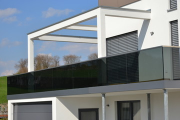 Balkon mit verglastem Edelstahl-Geländer an der Fassade eines modernen Wohnhauses