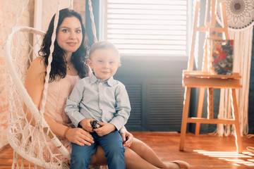 Mother sits with her little son in a chair.