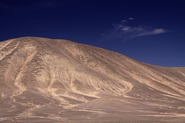 Fototapeta na wymiar View on barren dry brown isolated hill contrasting with deep blue sky in salar de atacama - Chile
