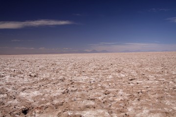 View over endless bright white and brown barren salt plateau into blurred horizon contrasting with deep blue sky - Salar (Salt flat) near San Pedro de Atacama, Chile