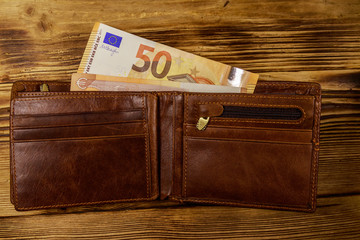 Open wallet with fifty euro banknotes on wooden background