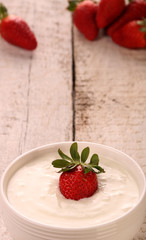 Healthy yougurt with stawberry on the white wooden table, selective focus