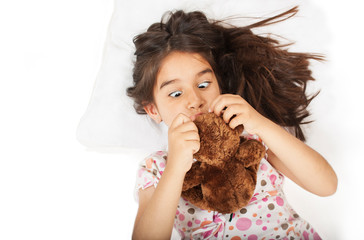  Little girl in bed with teddy bear the emotions of a child, white bed. Isolated on white background