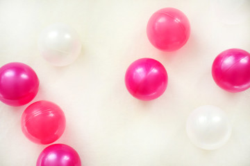 Many plastic pink and white balls on a white textile background. Children decoration concept.