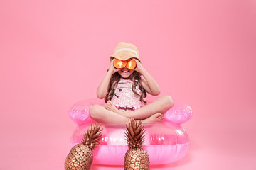 Funny little girl with citrus fruit on color background