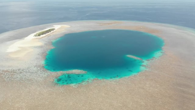 Aerial: Flying over idyllic atoll, travel destination Wakatobi National Park Indonesia Maldives Polynesia blue lagoon coral reef desert island white sand beach. Native cinelike D-log color profile