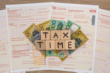 Australian dollar banknotes with wooden cubes at tax form