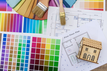 Close up of wooden house model with blueprint and color swatches