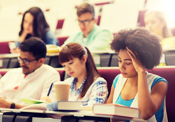 education, high school, university, learning and people concept - group of international students with notebooks and coffee writing test in lecture hall
