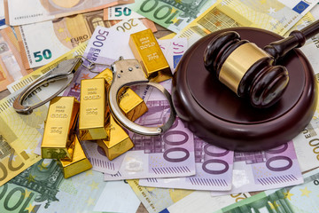 Gold bullions with judge's gavel and handcuffs on euro banknotes