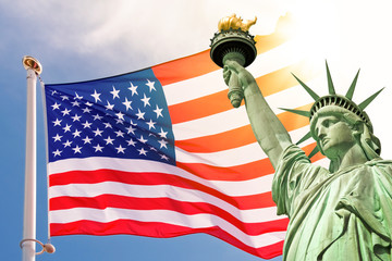 Statue of Liberty, sunny sky and US flag background, national american holiday, veterans day, memorial day, July 4, presidential election midterms 2026 © Delphotostock