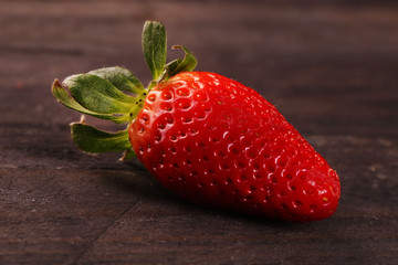 One strawberry fruit on black wood table background