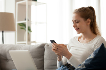 Smiling woman using phone, mobile device app, sitting on sofa