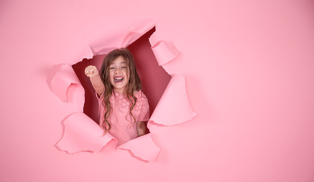 little girl playing superhero on pink background
