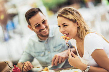 Couple eating pizza snack outdoors.They are sharing pizza and eating.