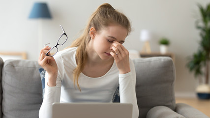 Woman taking off glasses, suffering from eyes fatigue after computer work