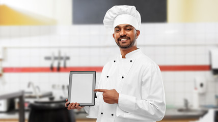 cooking, technology and people concept - happy male indian chef in toque with tablet computer over restaurant kitchen background