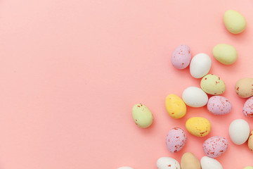Happy Easter concept. Preparation for holiday. Easter candy chocolate eggs and jellybean sweets isolated on trendy pastel pink background. Simple minimalism flat lay top view copy space
