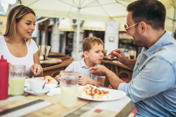 Obraz na płótnie Canvas Portrait of happy family spending time in pizzeria