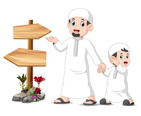 a child with his father is standing and posing near the blank wooden signpost