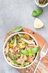 Salad - penne pasta with tomatoes, pesto, basil and lemon. Top view. Copy space. Horizontal.