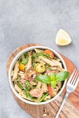 Salad - penne pasta with tomatoes, pesto, basil and lemon. Top view. Copy space. Horizontal.