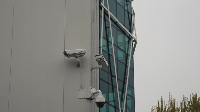 Outdoor video surveillance and security cameras installed on the modern business wall. Dome security camera on a commercial building. CCTV system on buildings