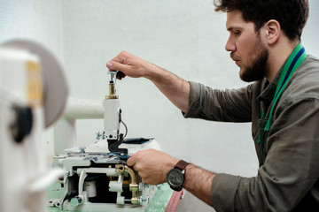 A master is sewing details for future product made of genuine leather