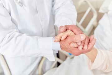 Fürsorglicher Arzt hält Hand eines Patienten
