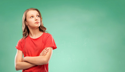 school, education and people concept - teenage girl in red t-shirt with crossed arms looking aside over green chalk board background