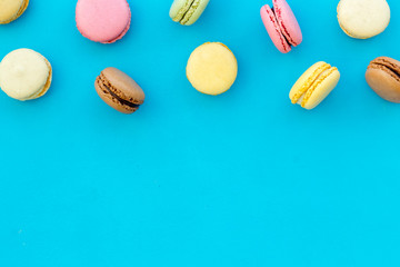 Obraz na płótnie Canvas sweet dessert pattern with macarons on blue background flat lay mockup