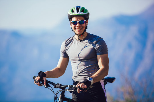 Portrait of mountain biker with helmet and sunglasses listening to music and smiling.